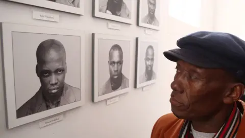 AFP Lazarus Molatlhegi looks at a picture of his father Thomas Molatlhegi in Pretoria, South Africa on 15 August 2018