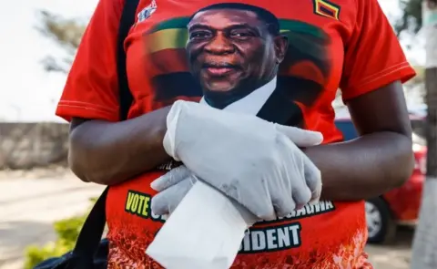AFP A supporter of Zimbabwe"s ruling ZANU-PF party wears latex gloves as the president visits a medical camp for people suffering from cholera set up outside the Glen View polyclinic on September 19, 2018, in Harare.