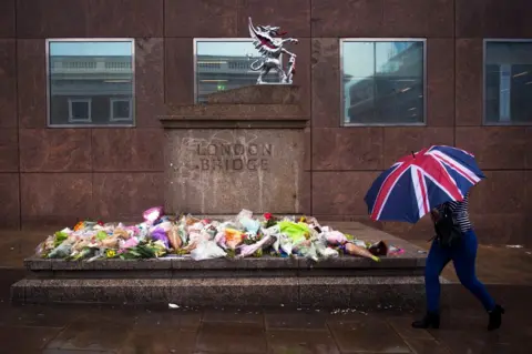 EPA A member of the public passes flowers and tributes left for victims of the London Bridge terror attacks