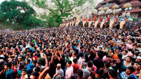 Getty Images Thousands gathers before a temple in Kerala. Ceremonial elephants can be seen in the background.