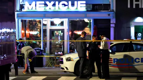 Getty Images Police officers stand outside a restaurant after a shooting in Washington, DC, on July 22, 2021