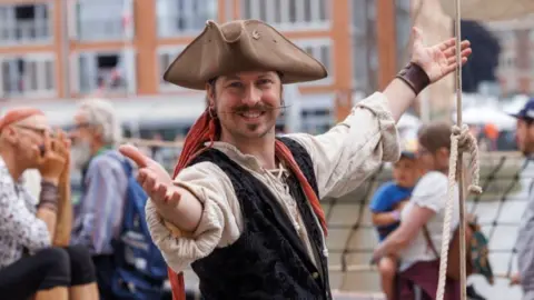 Visit Gloucester Gloucester Tall Ships Festival character in pirate costume smiling at the camera