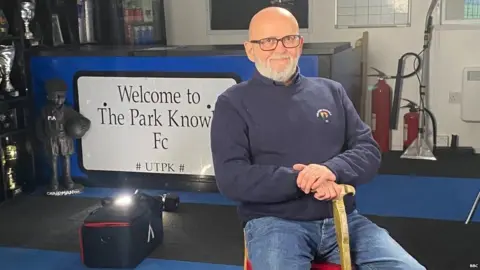 Mike Alden sat in front of a Park Knowle FC sign