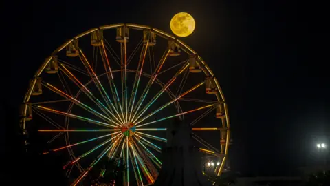 Yassine Gaidi/Getty Images The full moon pictured by a Ferris wheel in Tunis, Tunisia - Friday 5 May 2023