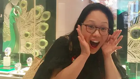 Yiying Lu Irene Cho in front a store with peacocks in the window display