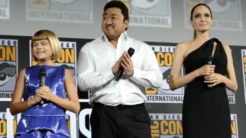 Getty Images Lia McHugh, Dong-seok Ma and Angelina Jolie stand on stage