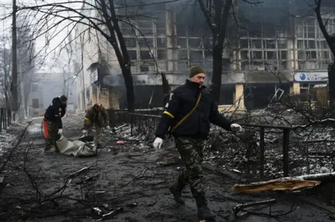 Getty Images Police officers remove the body of a passerby killed in yesterday's airstrike that hit Kyiv's main television tower in Kyiv on March 2, 2022.