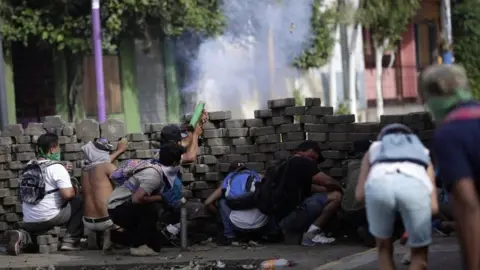 EPA Protesters take cover behind a makeshift barrier during ongoing protests in Masaya, Nicaragua, 09 June 2018. Nicaragua saw renewed protests after President Daniel Ortega failed to respond to a letter calling for "democratization" of the country.