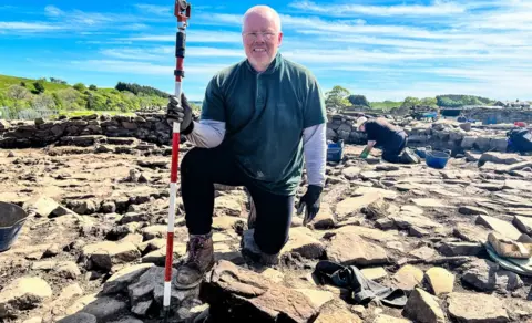 The Vindolanda Trust Dylan Herbert with the stone at Vindolanda