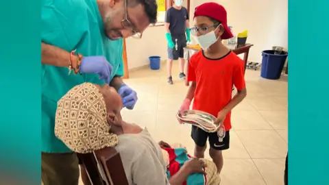 Vivak Shah Dr Vivak Shah treats a patient as one of his sons standby to help