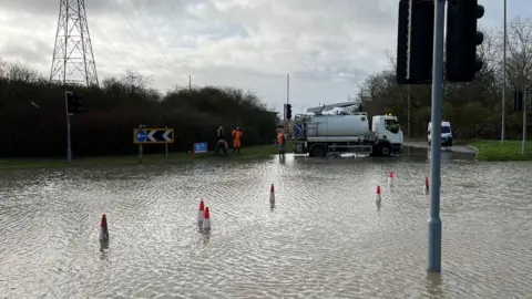 BBC A flooded roundabout with people working on it