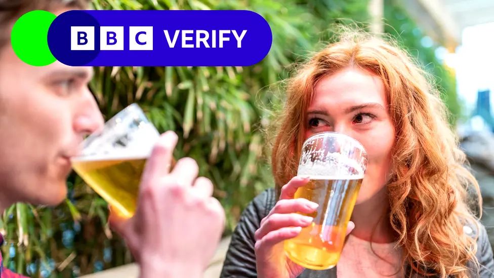 A man and a woman drink beer in a pub garden