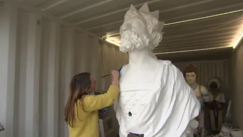 Painter Sarah Brown working on a figurehead