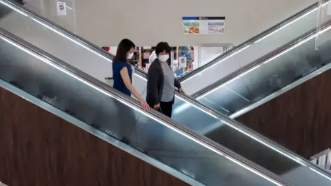 Getty Images People wearing face masks on an escalator in a shopping centre in Japan.