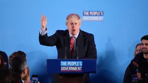 AFP Boris Johnson at podium delivering speech at QE2 centre in central London