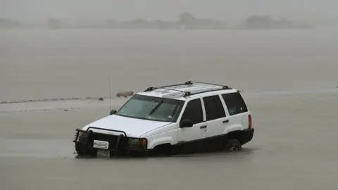 AFP A white SUV car is seen submerged