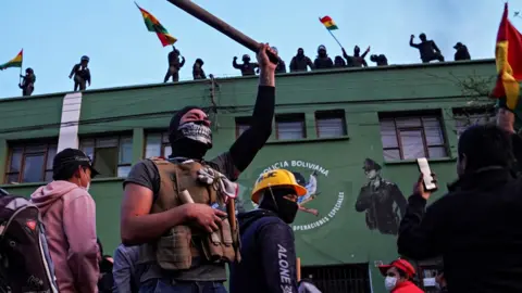 Reuters Opponents of Bolivia's President Evo Morales react as police officers stand on the roof of their headquarters, in Cochabamba, Bolivia