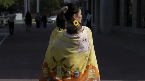 Tariq Zaidi Mother and child walk around in Pyongyang