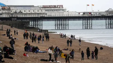 PA Media People sit on Brighton beach, East Sussex. Picture date: Friday April 2, 2021.