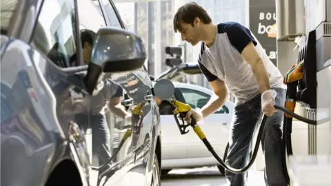 PhotoAlto/James Hardy Man filling up car