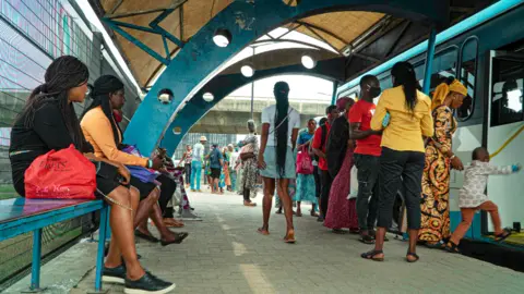 BBC/Ayo Bello Commuters at a bus stop in Lagos,Nigeria