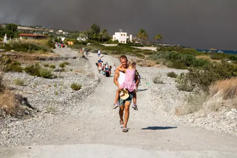 Anadolu Agency / Getty Images Tourists are evacuated as huge wildfire rages on Rhodeson 22 July 2023