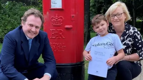 Tom Tugendhat Tom Tugendhat, Tony and his mother Paula Hudgell with the Prime Minister’s Points of Light Award