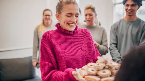 Getty Images Woman offers cake in an office (stock photo)