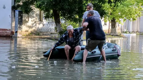 EPA-EFE/REX/Shutterstock An elderly man is helped to get in an inflatable boat in Kherson, southern Ukraine. Photo: 6 June 2023