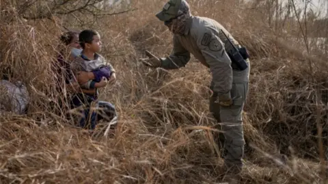 Reuters Migrants crossing into the US are stopped by an official in Texas