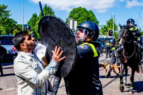 Robin Utrecht/SOPA Images/ Getty Images A demonstrator clashes with a riot police officer