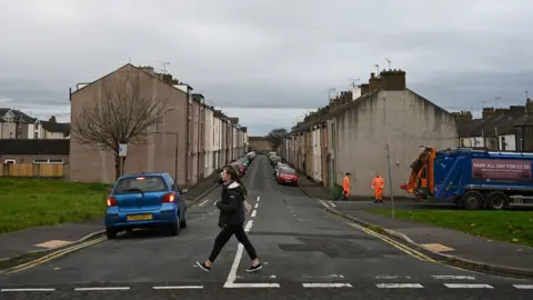 AFP Refuse collectors work on a street in Workington, north west England on November 6, 2019