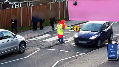 Car drives into lollipop lady's stick