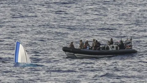 Royal Navy A submerged dinghy next to a Navy boat