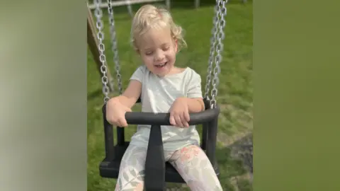 Family handout Mia in a swing laughing