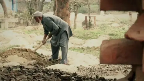 Mohd Shabir Mohammad Shareef levelling a grave