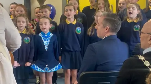 Paul GIvan listens to children at the school sing