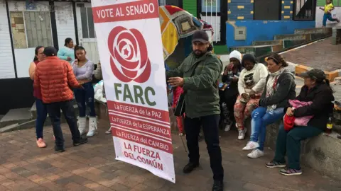 A man holds up a banner urging to vote for the Farc