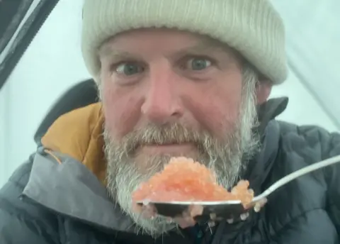 Mike Keen Mike Keen eating in his tent in Greenland