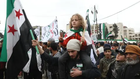 EPA Syrians in opposition-held Idlib province gather to commemorate the 12th anniversary of the uprising against President Bashar al-Assad (15 March 2023)