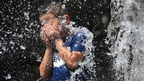 AFP A child cools off under a fountain in Montpellier, southern France - 27 June