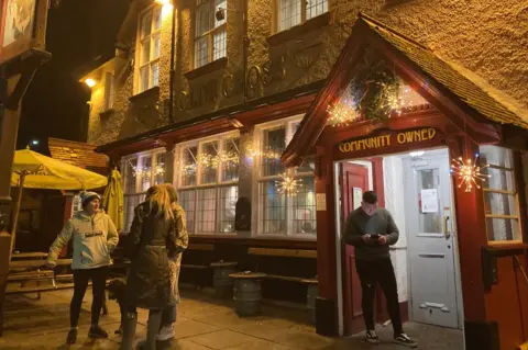 People outside Ye Olde Cross in Ryton with a sign saying Community Owned