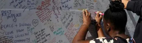 Getty Images A woman writing a message of condolence