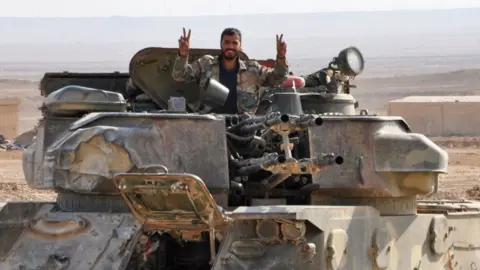 Getty Images A soldier from the Syrian government forces flashes the 'V' for victory sign in the eastern Syrian city of Deir Ezzor during an operation against Islamic State (IS) group jihadists