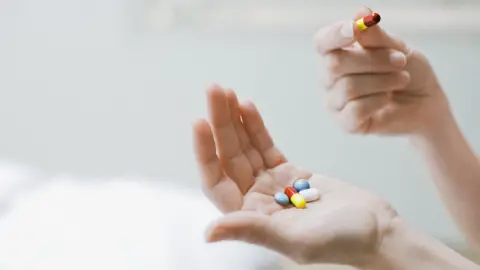 Getty Images Hand holding pills