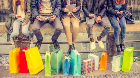 Getty Images Friends with shopping bags and electronic gadgets