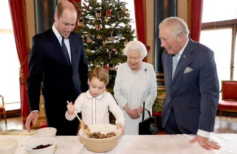 PA Media Queen Elizabeth II, the Prince of Wales, the Duke of Cambridge and Prince George preparing special Christmas puddings in the Music Room at Buckingham Palace, London, as part of the launch of the Royal British Legion's Together at Christmas initiative