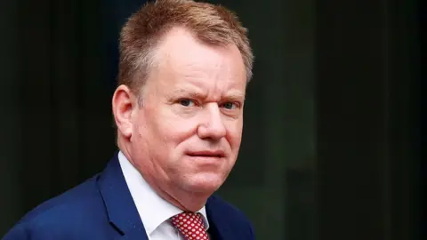 Reuters Lord Frost pictured from the shoulders up, looking towards the camera and dressed in a suit