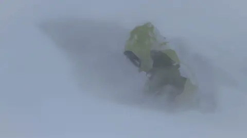 SAIS Southern Cairngorms SAIS team member digging an avalanche test pit in whiteout conditions in Southern Cairngorms