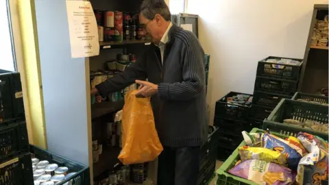 BBC A volunteer filling a bag with food